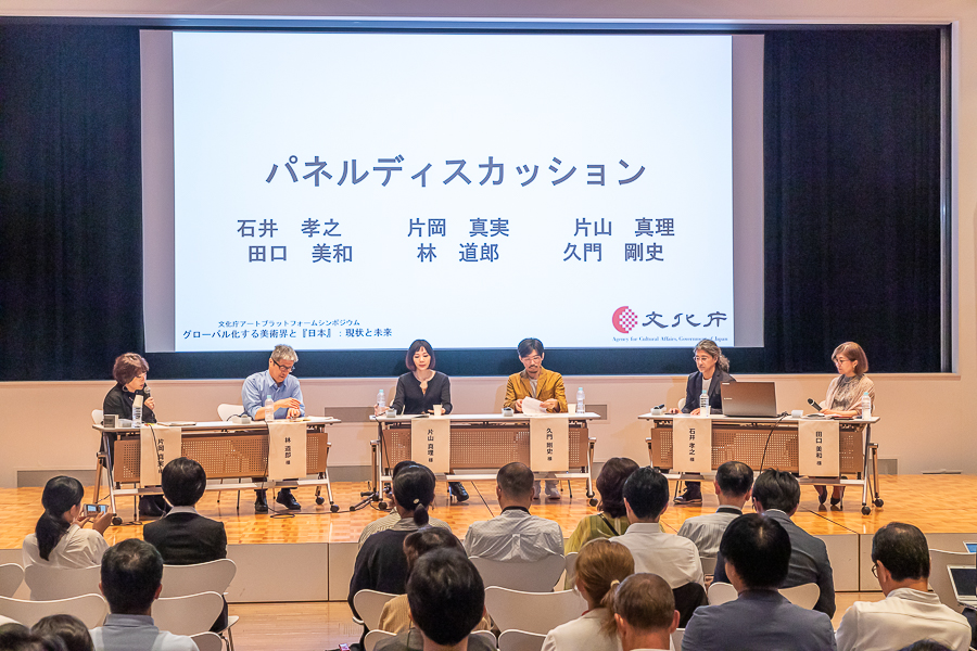 シンポジウム会場の壇上でパネルディスカッションをする6名の写真