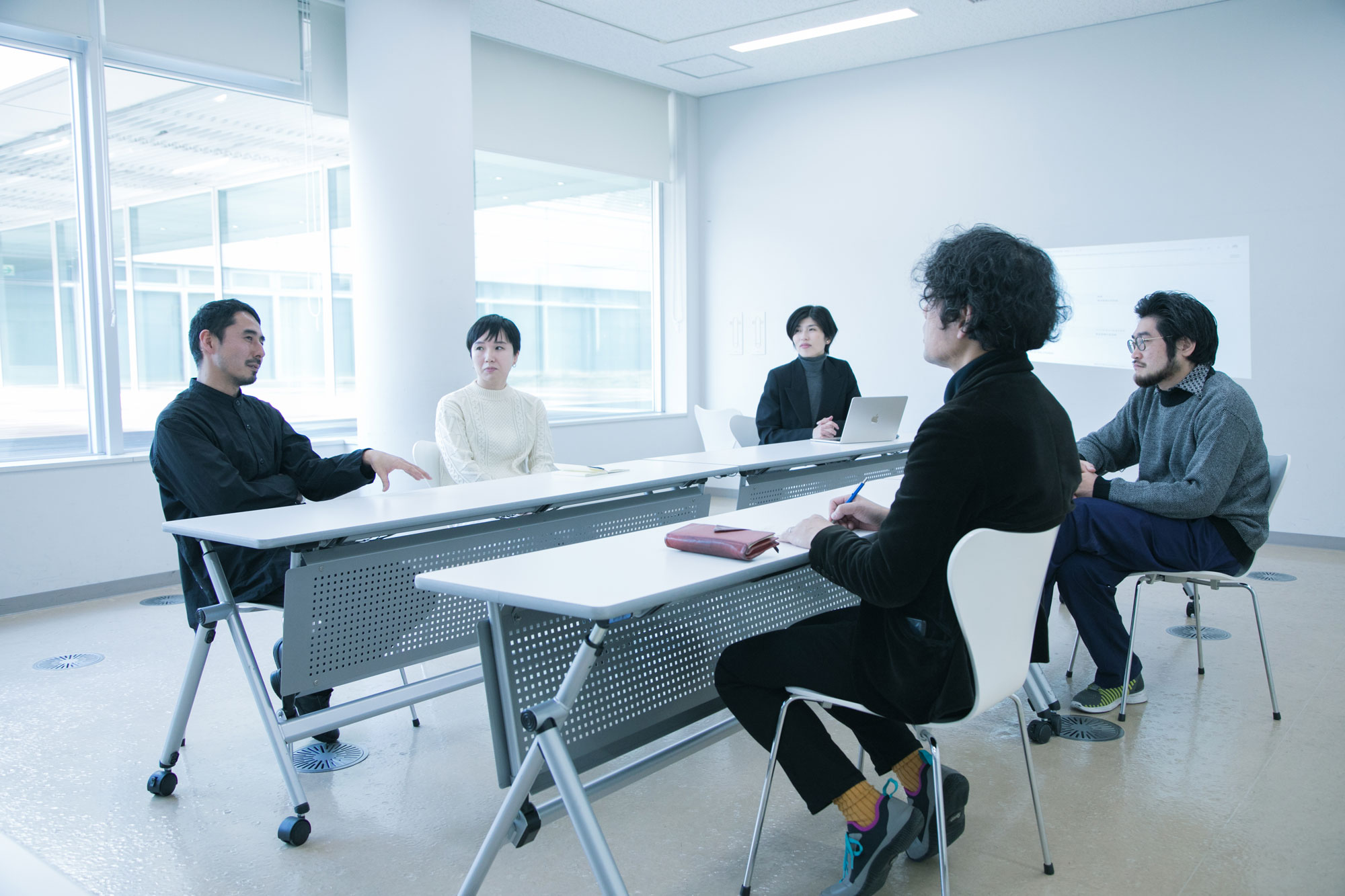 対談参加者5名が会議室で向かい合って座り、話し合っている写真