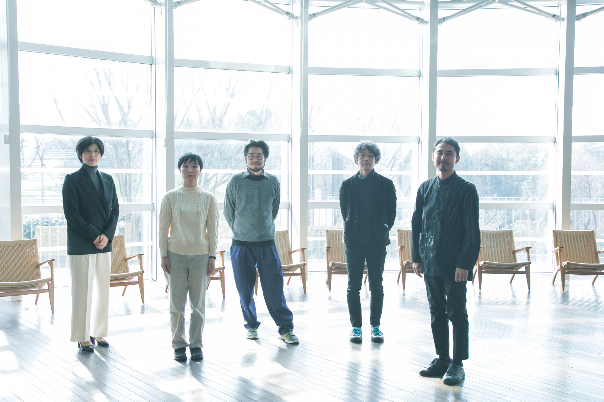 対談参加者5名が横並びに立ってこちらをみている写真。ガラス張りの部屋で、窓に沿って椅子が並んでいる