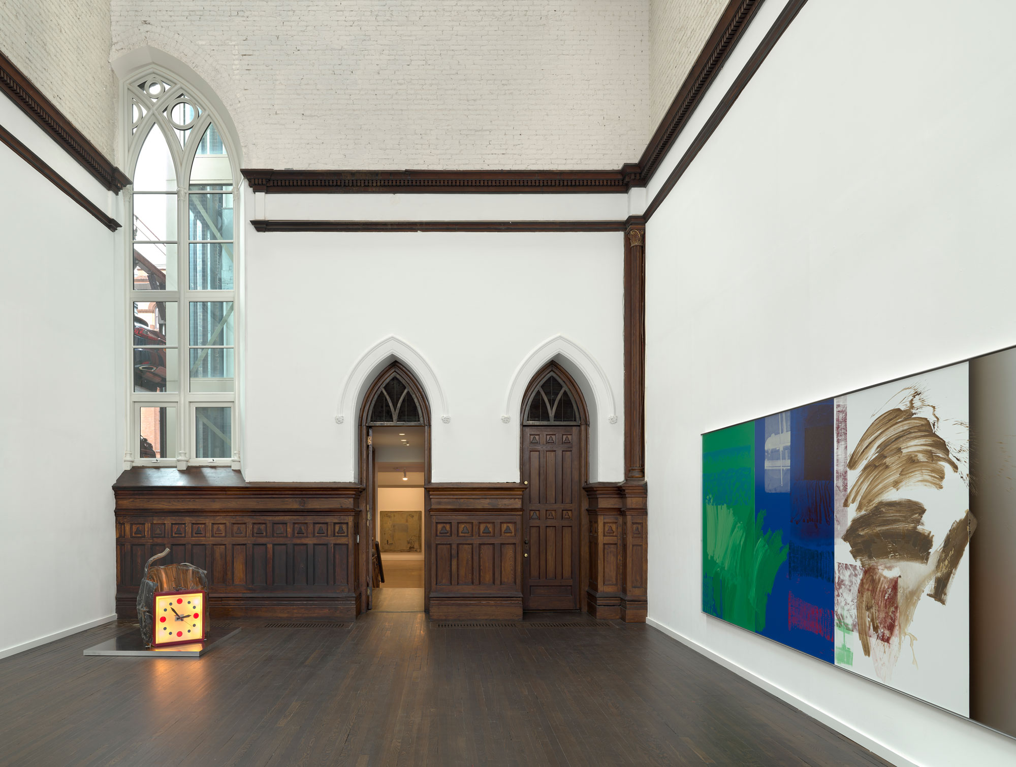 Photo of the room. There is a clock on the floor in the left corner. There are paintings hanging horizontally on the right wall.